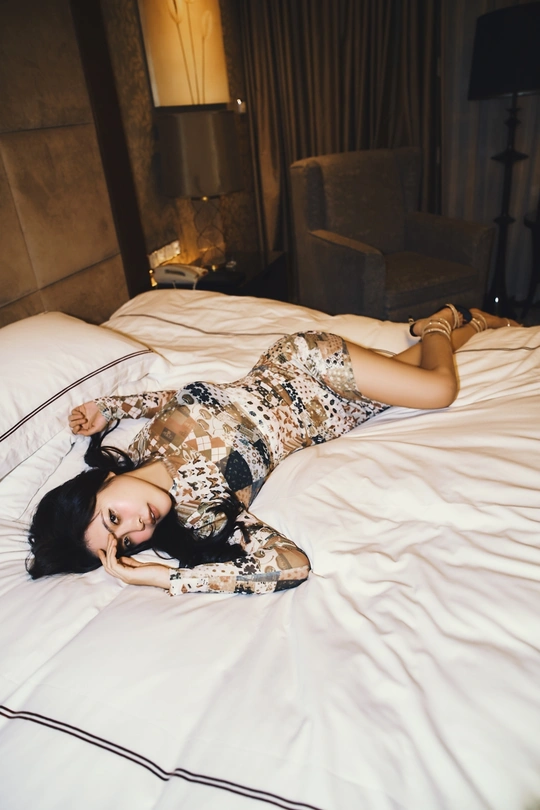 一个穿着白色连衣裙的美丽年轻女子躺在白色床上