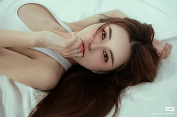 一个年轻美丽的女子躺在白色的床上 她的头发挡住了脸