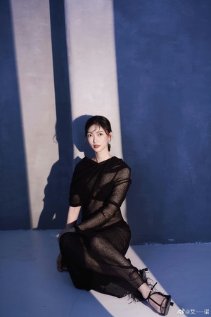 穿着黑色连衣裙的模特儿在蓝色墙壁前摆姿势
