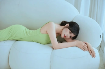 一个年轻女子躺在白色椅子的 bean bag 上。