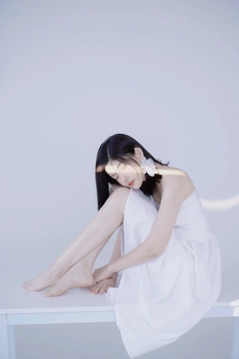 一个年轻女子穿着白色裙子坐在长凳上梳理她的头发