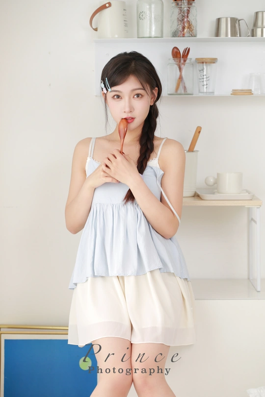 一位穿着白色连衣裙的年轻女子在厨房里