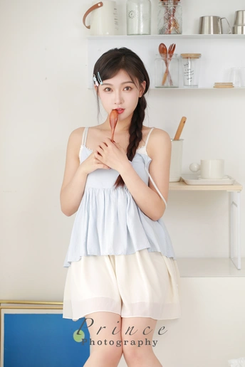 一位穿着白色连衣裙的年轻女子在厨房里