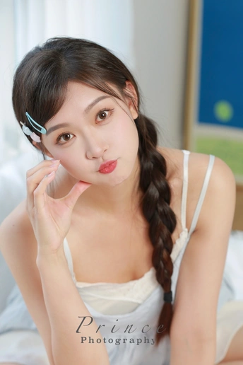 一个年轻女子在床上涂着妆 她的头发编成辫子。