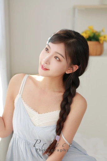 一位长发年轻女子穿着蓝色连衣裙坐在床上的肖像