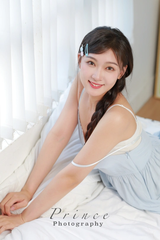 一个穿着蓝色连衣裙的年轻女子躺在白色床上