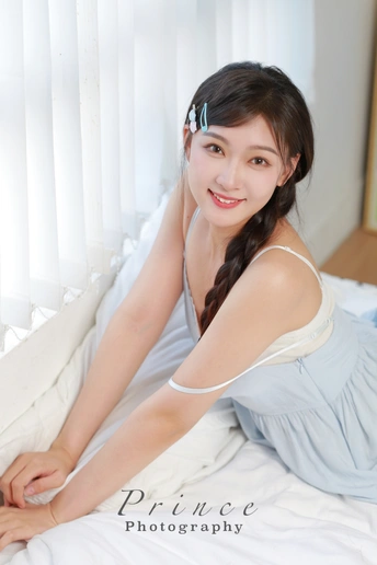 一个穿着蓝色连衣裙的年轻女子躺在白色床上