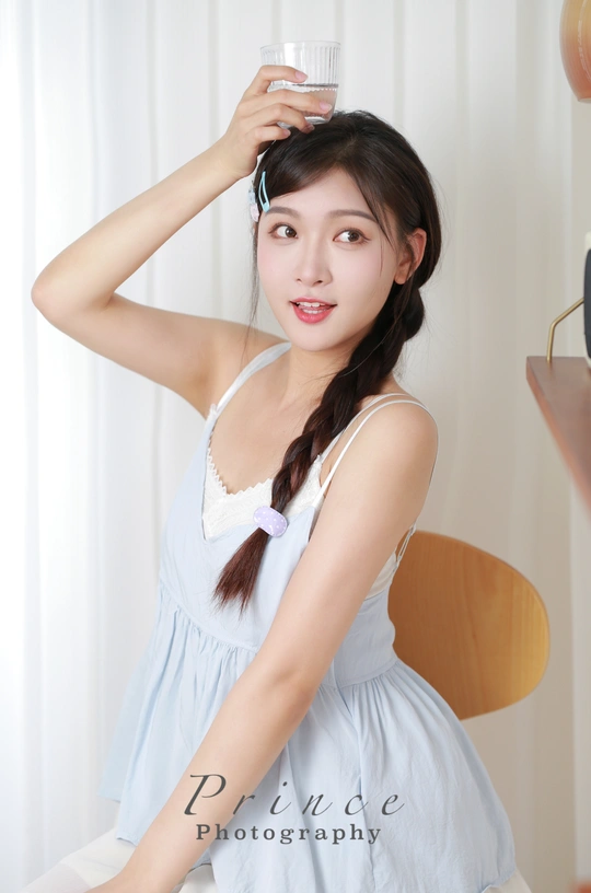 一个穿着白色连衣裙的年轻女子 手里拿着一杯水 头顶上还放着一杯饮料。