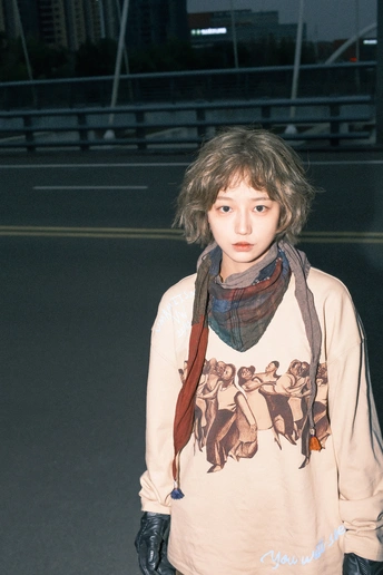 一个穿着运动衫和围巾的年轻女子站在滑板车上