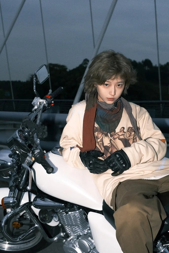 一个戴围巾的年轻男子坐在白色摩托车上