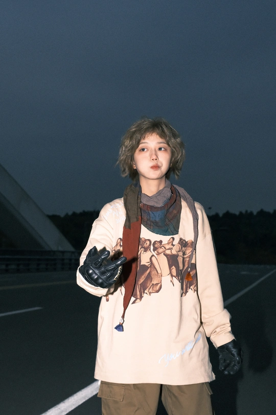 一个年轻女子站在滑板上 中间穿行在道路上 背景中一个男子站在桥上。