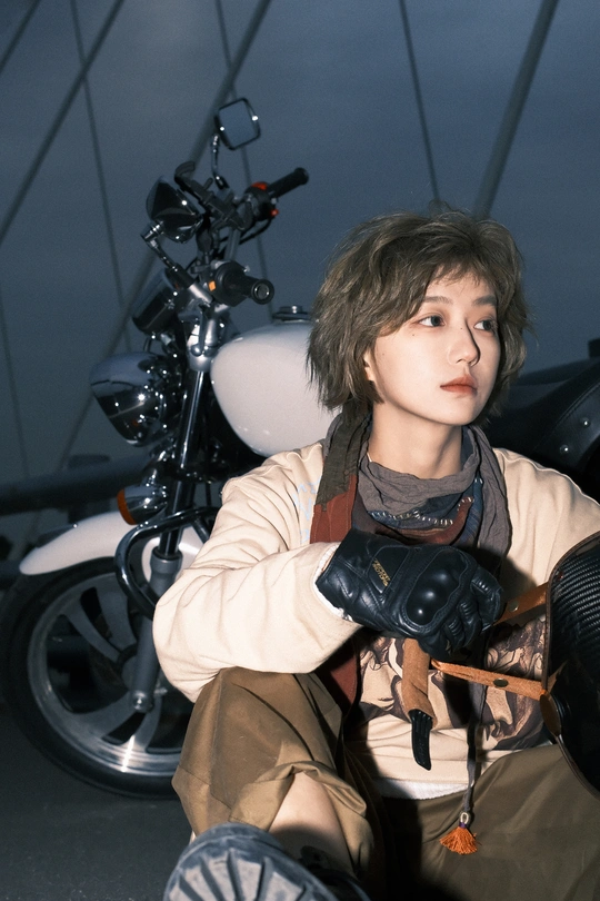 一个戴着手套的年轻男子坐在摩托车上 为相机摆姿势
