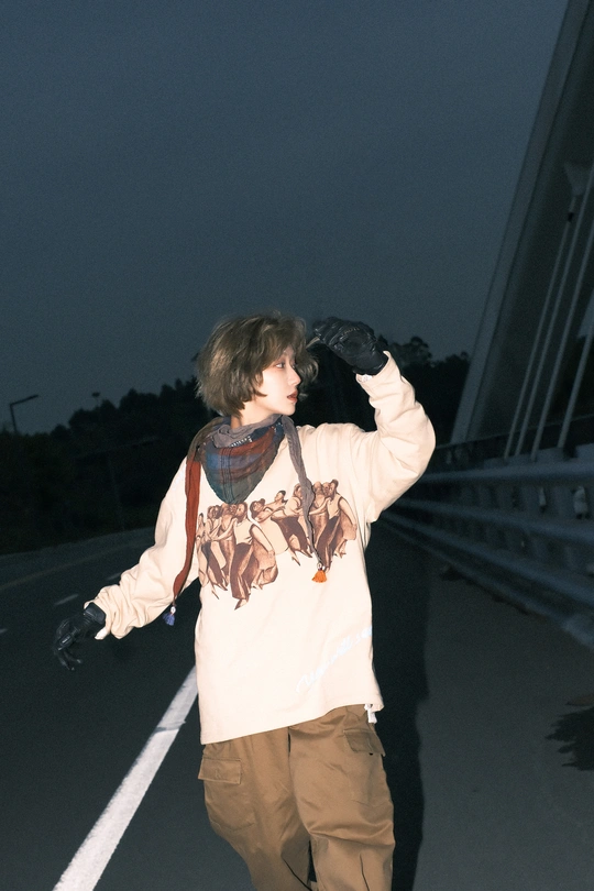 一个年轻人晚上骑着滑板在高速公路上滑行 而另一个人站在桥上拿着手套。