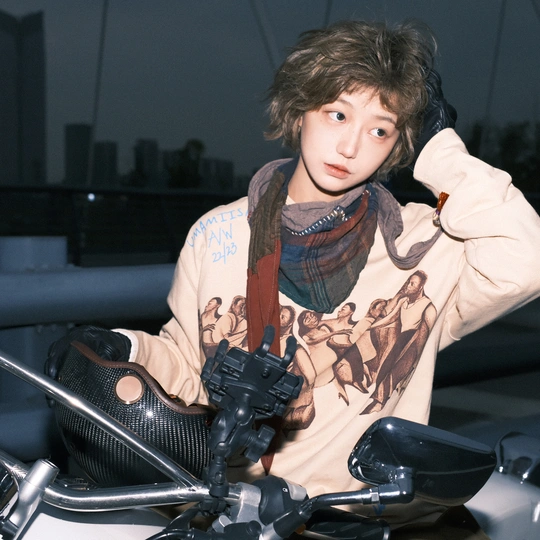 一位戴围巾的年轻男子正在给相机拍照 而一位年轻女子则坐在摩托车上。