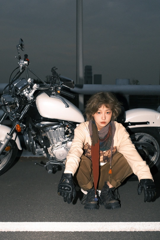 一位年轻女子跪在白色摩托车前