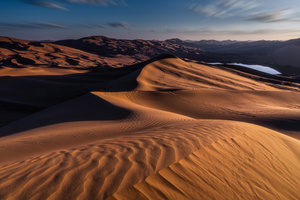 夕阳或日出时的大漠沙丘 太阳照亮远处的山脉。
