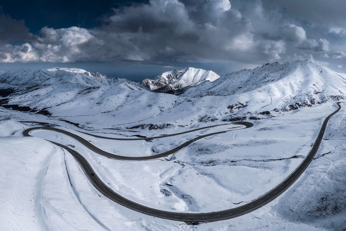 穿越冬季山脉中的一个被雪覆盖的山口的一条蜿蜒的山路
