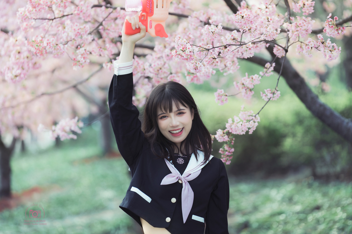 一个穿着校服的年轻女子手里拿着一朵粉红色的花