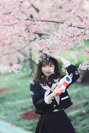 一个女孩在一棵开花的树下抱着泡泡