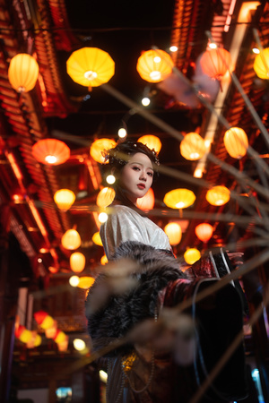 一位穿着传统服装的年轻女子站在点亮的伞下