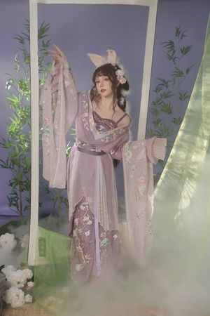 一位穿着粉红色和紫色裙子的女人在一个紫色的房间里摆姿势 紫色房间里有紫色的云彩。