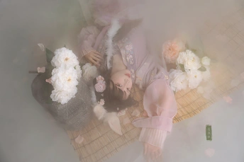 一个被白色花朵围绕的女人和一篮子洋娃娃