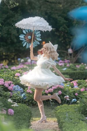 一位穿着白色连衣裙的年轻女子手持雨伞在花丛中奔跑