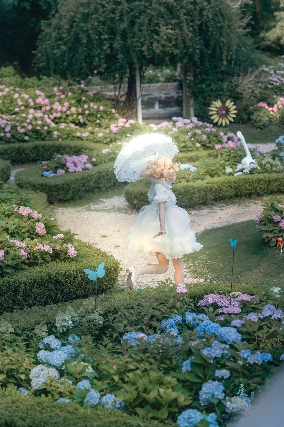 一位穿白裙子的女人在花丛中拿着一把伞