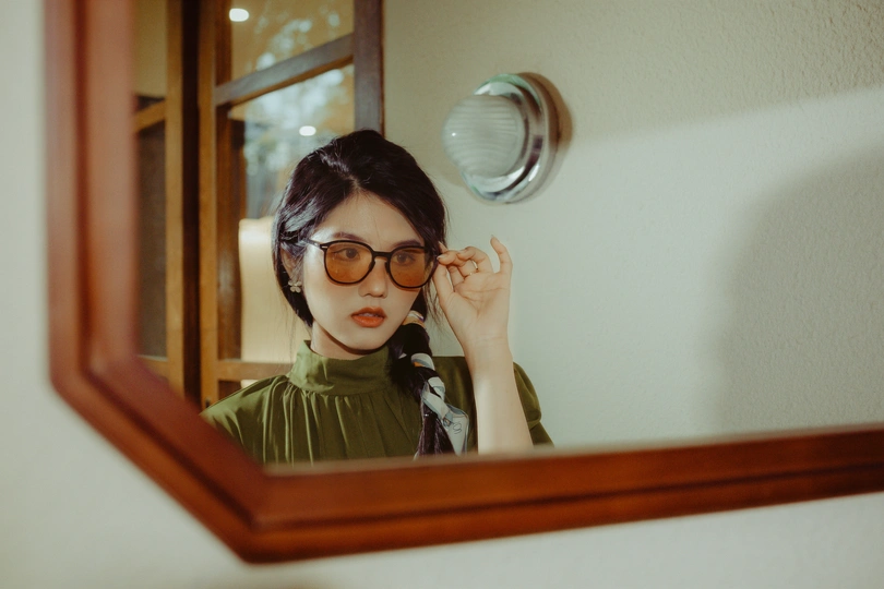 一个戴眼镜的年轻女子正在浴室镜前看自己的倒影
