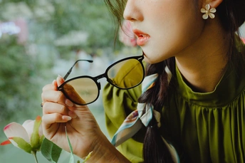 戴眼镜的年轻女子手持一束花靠近窗户