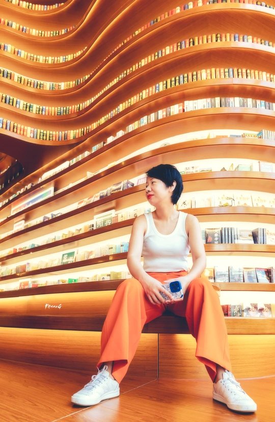 一个穿着橙色裤子的女人坐在一栋楼的地板上
