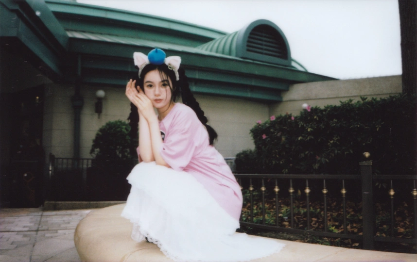 一位穿着白色连衣裙的年轻女子坐在建筑物前的一张长椅上