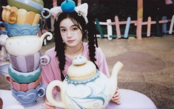 一个年轻女子坐在桌子旁 茶壶和杯子在桌子上。