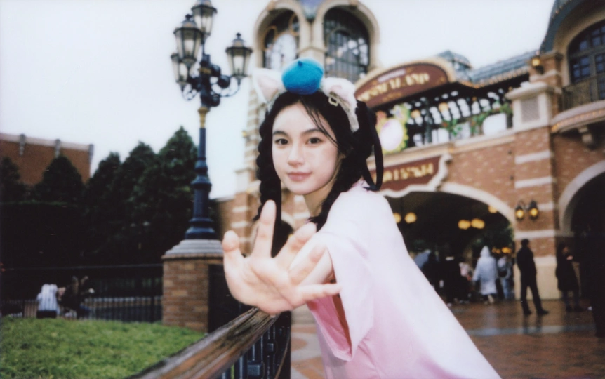 一位穿着粉红色裙子的女士在迪士尼主题公园前摆姿势