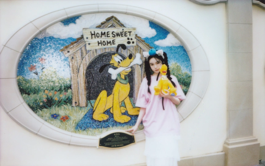 一位女子拿着一张女孩站在壁画前的照片