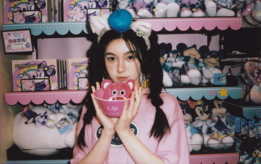 一位年轻女子拿着一个粉色杯子在玩具架前