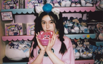 一位年轻女子拿着一个粉色杯子在玩具架前