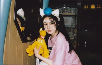 一位穿着粉红色衣服的年轻女子抱着一个黄色毛绒玩具