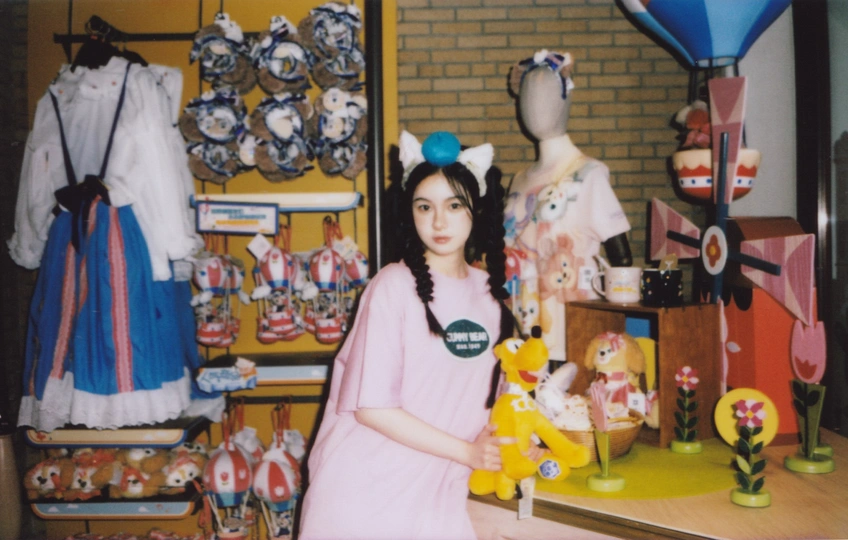 一个穿着粉红色连衣裙的年轻女子抱着一只泰迪熊站在玩具房间中