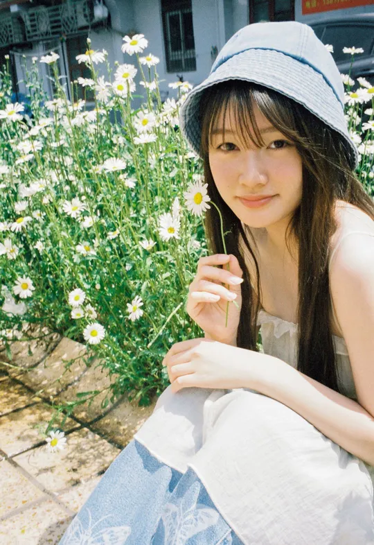 一位穿着蓝色帽子的年轻女子坐在白色花丛中