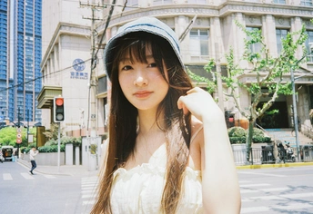 一位穿着白色连衣裙和帽子的小姐在城市的街道上为相机摆姿势