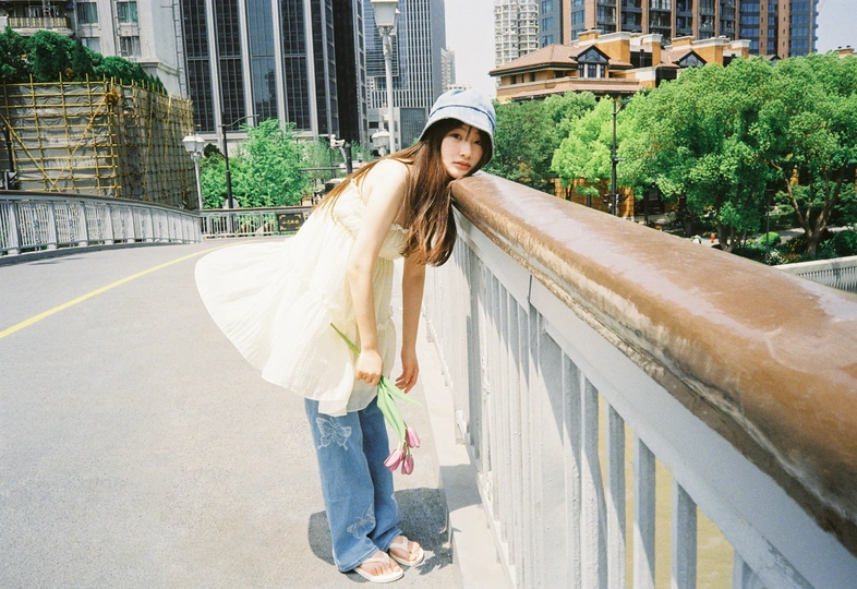 一位戴帽子和提包的年轻女子站在桥上