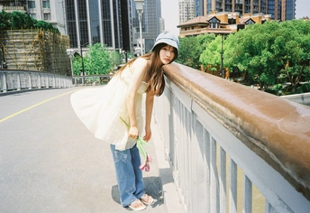 一位戴帽子和提包的年轻女子站在桥上