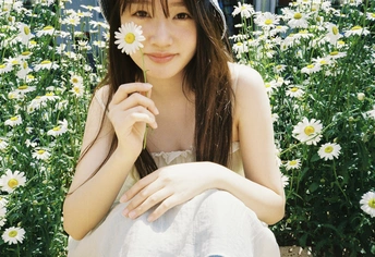 一位戴着帽子的年轻女子坐在白色花丛中