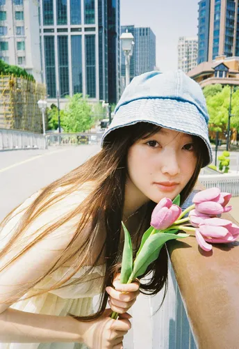 一位戴蓝帽子的年轻女子手拿粉色花朵