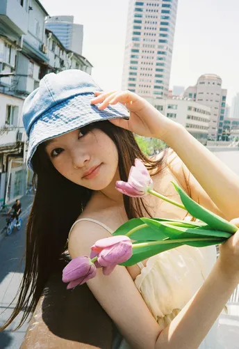 一位穿着蓝色帽子 在城市中拿着花的女青年