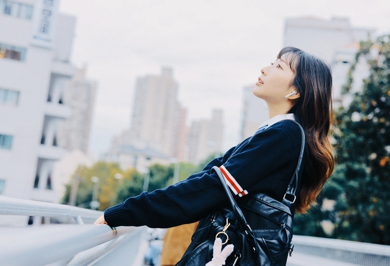 城市中一位年轻女子抬头望向天空的照片