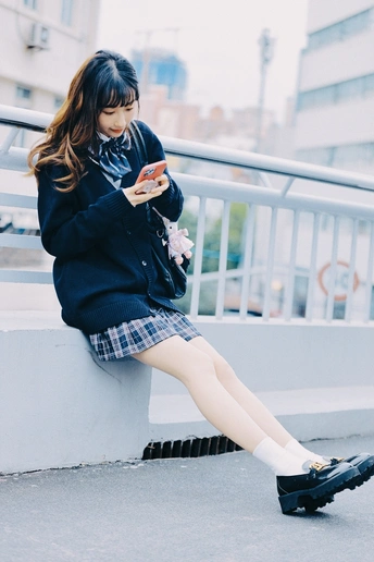 一个年轻女子坐在墙上看着她的手机