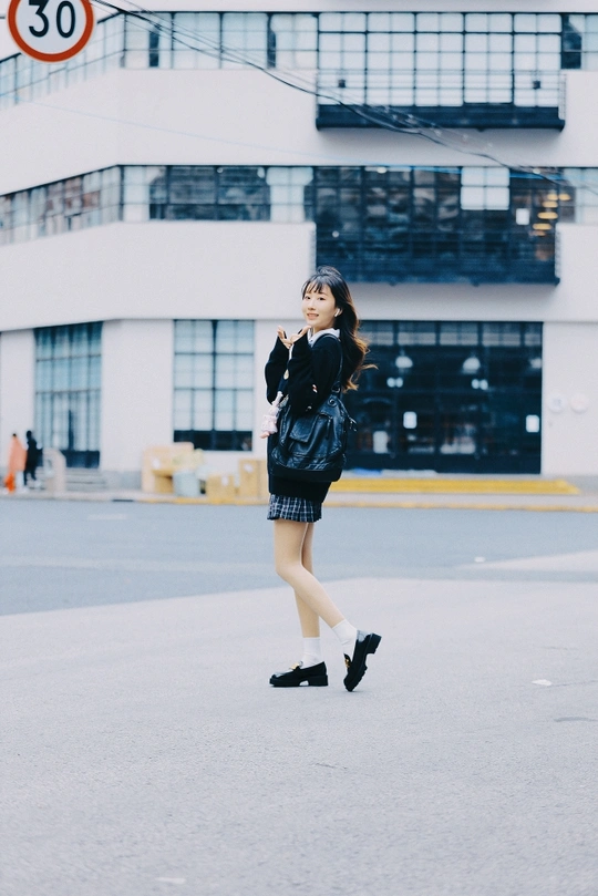 一位穿着黑色连衣裙的年轻女子正在街上走