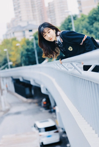 一位穿着黑色连衣裙的年轻女子在桥上摆姿势